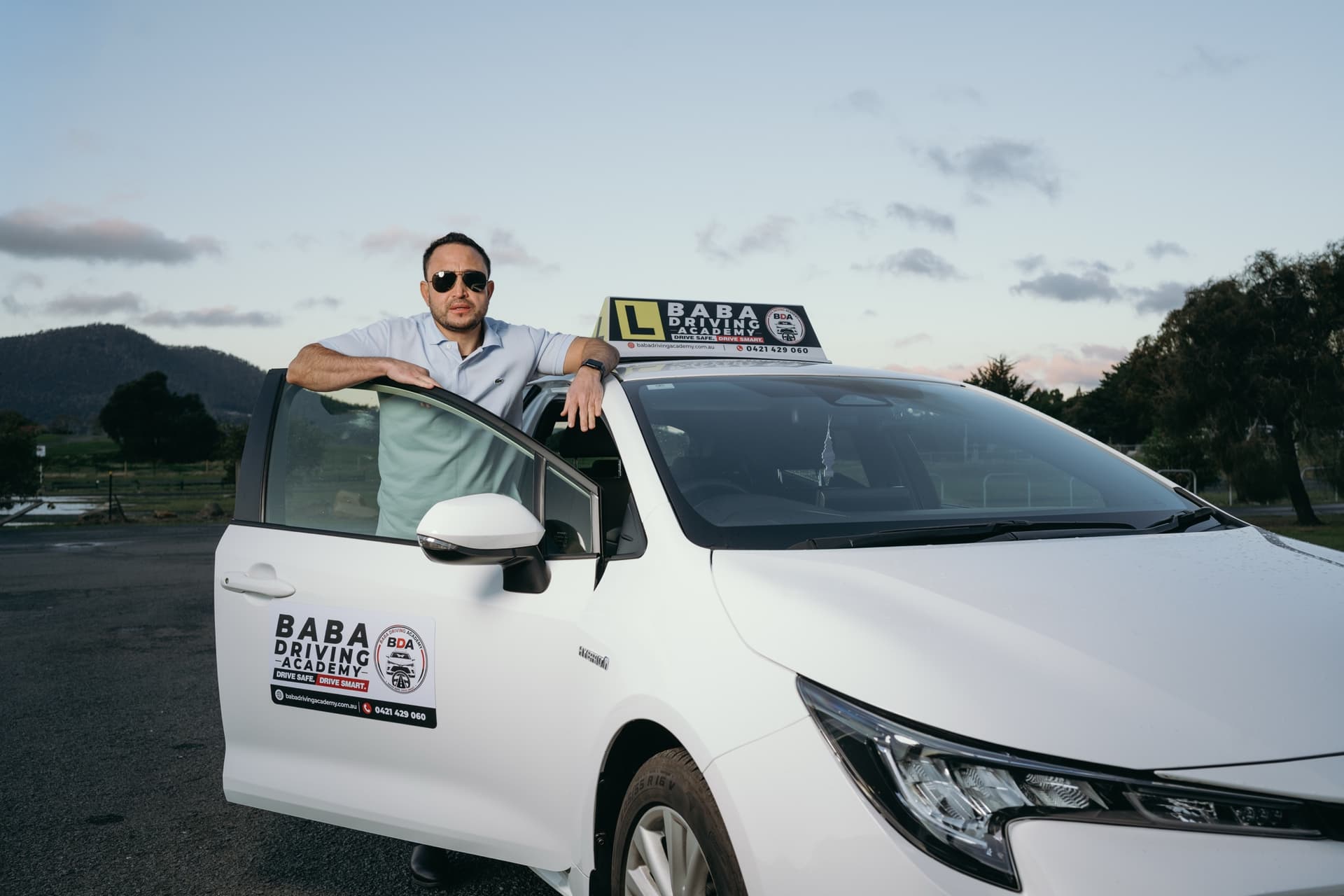Indra Khadka, driving instructor at Baba Driving Academy, beside the training vehicle.